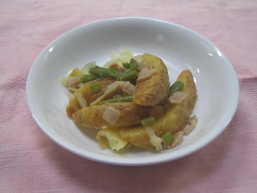 白色の皿の上に、輪切りにしたジャガイモやベーコン、いんげんなどの野菜が盛りつけられた完成したリエージュ風サラダの写真