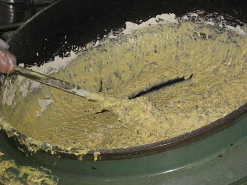 大きな釜に入った蒸しパンの材料をヘラでを混ぜている写真
