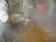 大豆をゆがいた煮汁を小鍋ですくっている写真