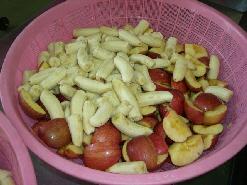 大量の芯がなくなったりんごとバナナがピンクのざるに入っている写真