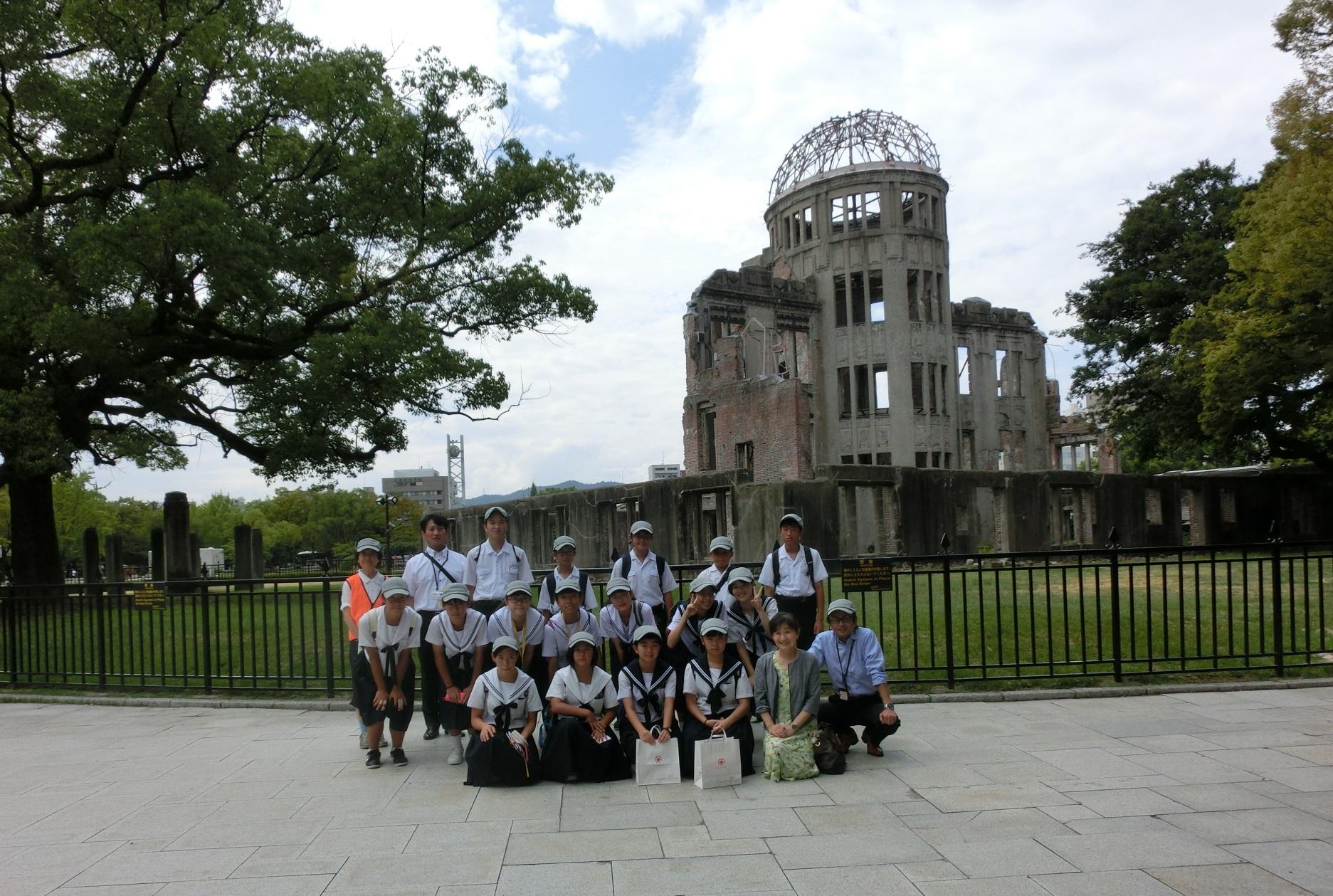 原爆ドームの前で生徒と引率の方が3列に並んで笑顔で映っている集合写真