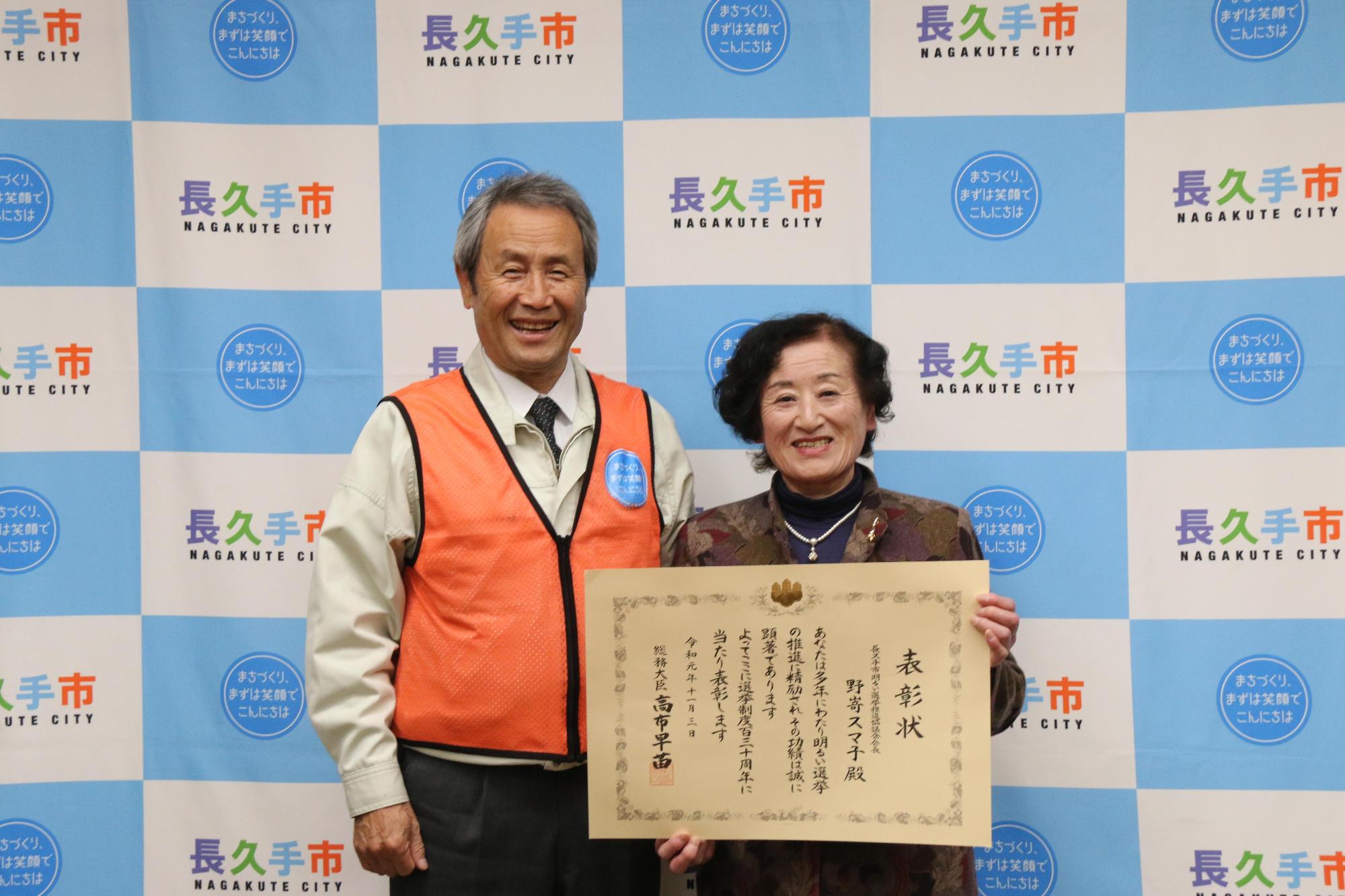 総務大臣表彰を受賞した野嵜スマ子さんが賞状を手に持って笑顔で市長と写っている写真